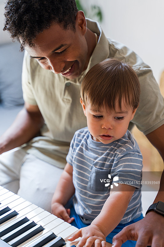 父亲教他的婴儿儿子弹钢琴图片素材