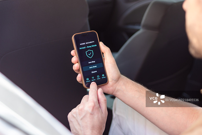 男子在车内使用智能手机应用程序设置家庭安全系统图片素材