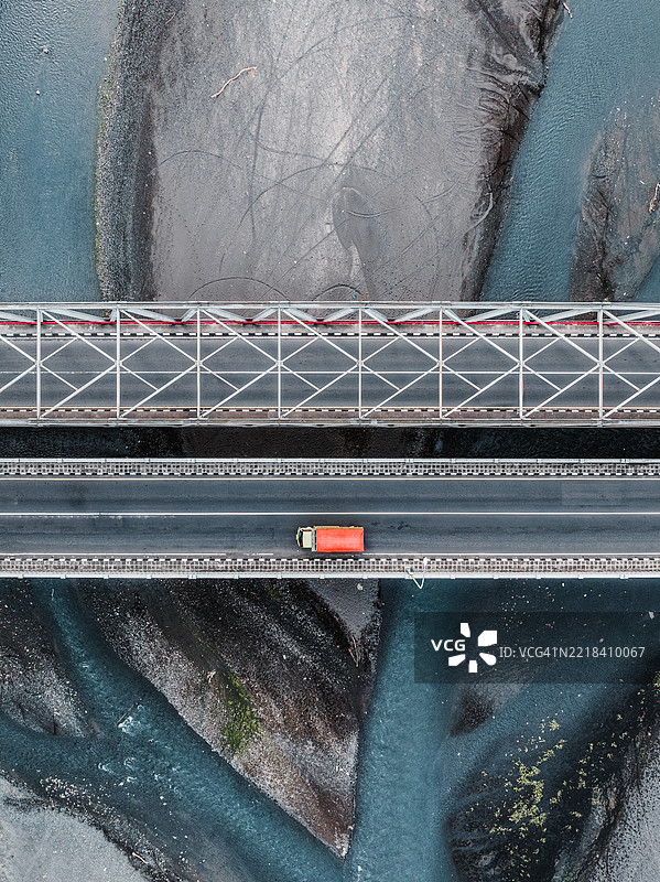 无人机拍摄的图像，俯瞰一辆卡车在印度尼西亚巴厘岛的海峡上方的桥上行驶，正值退潮时。图片素材