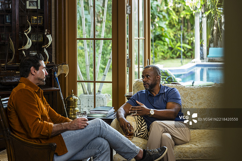 成熟男性朋友们在喝威士忌时讨论。图片素材
