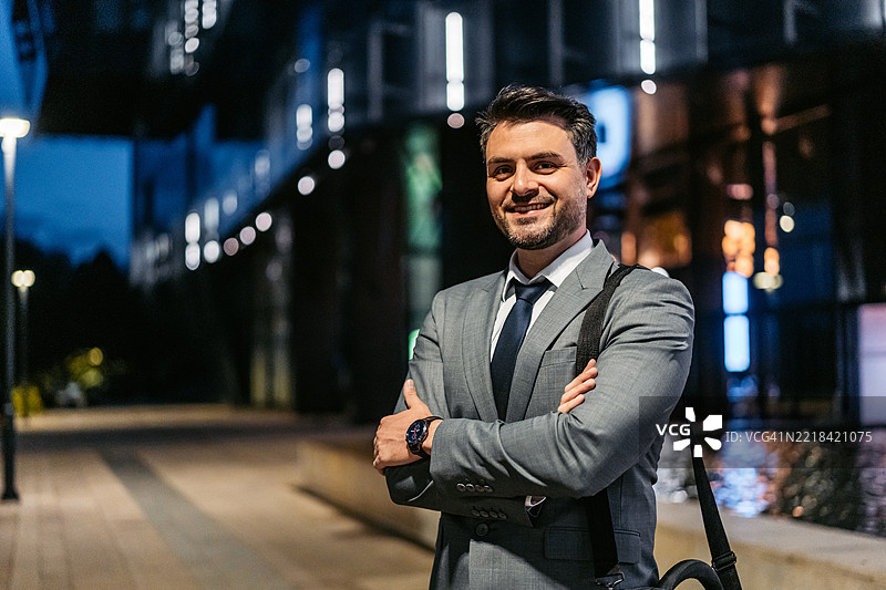 中年商人在夜晚站在一座企业大楼前图片素材