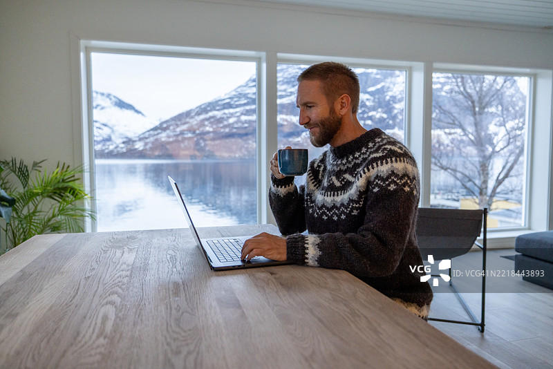 穿着北欧毛衣的男子在家办公室进行视频通话，背景是美丽的风景图片素材