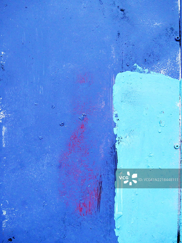 铆接金属墙上的蓝色和青绿色画作。粗糙的纹理。阳光。自然色彩。比利时布鲁塞尔。图片素材