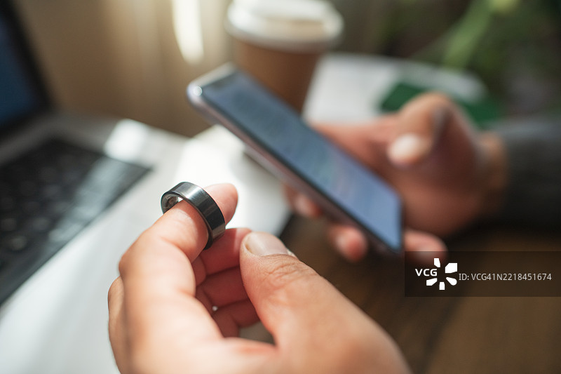 室内佩戴智能戒指和使用智能手机的男子图片素材