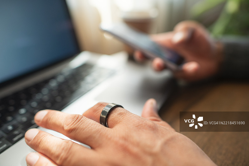 戴着智能戒指的男子在室内使用笔记本电脑图片素材