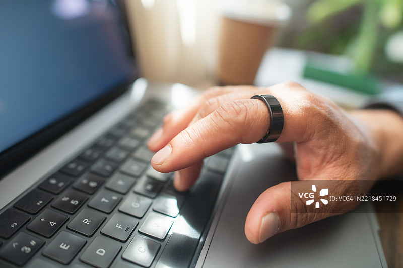 戴着智能戒指的男子在室内使用笔记本电脑图片素材