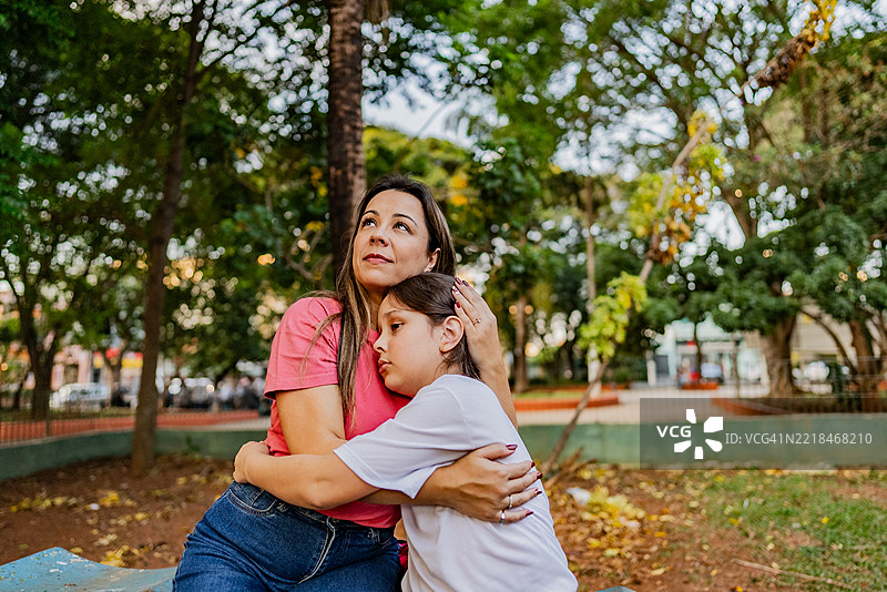 母亲在公园里安慰伤心的女儿。图片素材