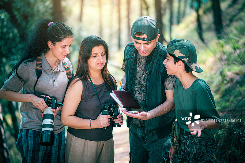 一位印度父亲在家庭观鸟旅行中教他的妻子、儿子和女儿如何使用指南针。图片素材