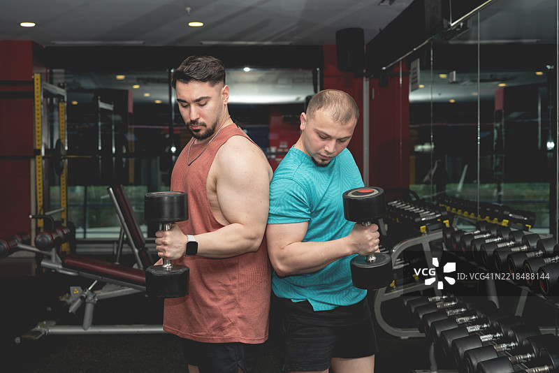 两名男子在健身房背靠背进行前臂锻炼的镜头图片素材