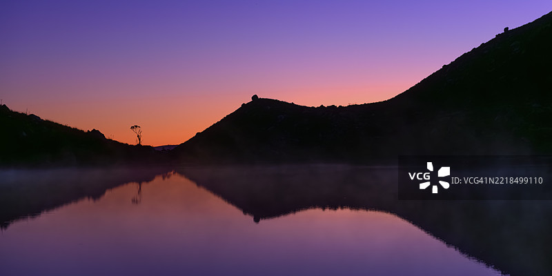 日落时分宁静的湖泊与剪影般的山丘图片素材