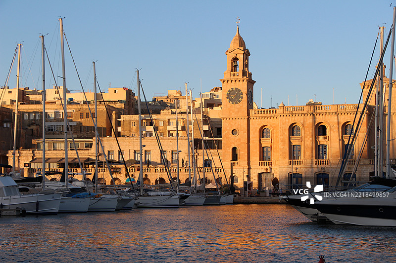 日落时分，停靠在港口的船只与历史建筑图片素材