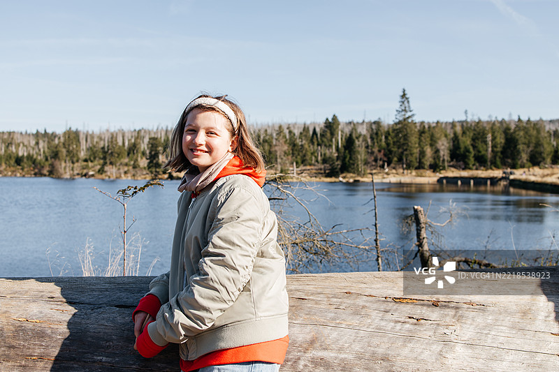 阳光明媚的春天，一位年轻女孩在山林湖边微笑图片素材