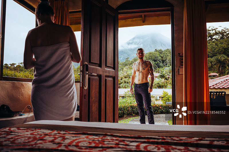 浪漫情侣在哥斯达黎加酒店房间中拥抱，窗外可见火山景观图片素材