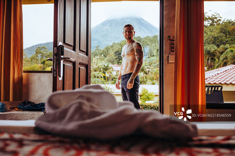 浪漫情侣在哥斯达黎加酒店房间中拥抱，窗外可见火山景观图片素材