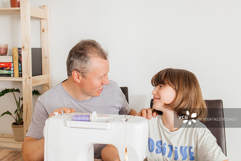 少女和爸爸在缝纫机上改造和缝制旧牛仔裤图片素材