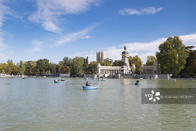 马德里埃尔雷蒂罗公园的湖面上有船只，背景是阿方索十二世纪念碑图片素材