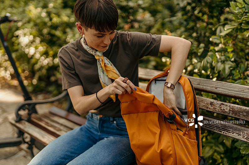 年轻女性坐在长椅上翻找背包图片素材