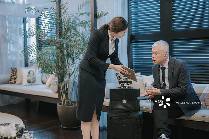 亚洲女性酒店经理在办理入住时协助老年客人进行讨论图片素材