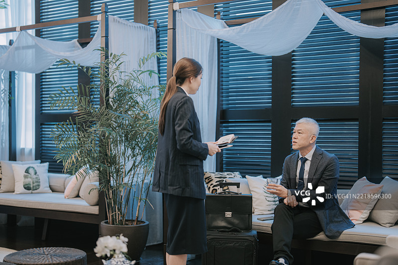 亚洲女性酒店经理在办理入住时协助老年客人进行讨论图片素材