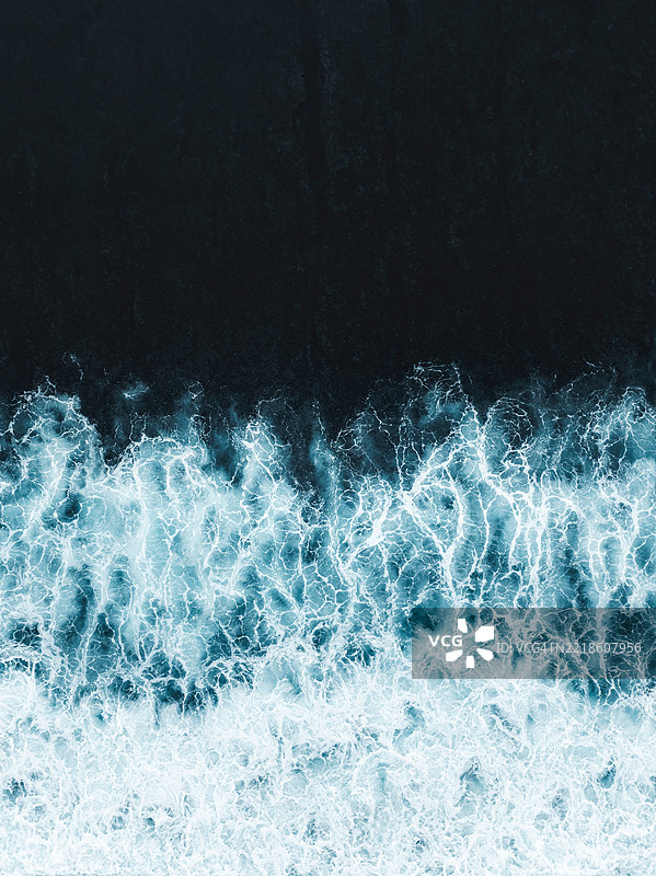 抽象无人机照片，展示了印度尼西亚巴厘岛巴东区黑沙滩上海浪拍打的景象。图片素材