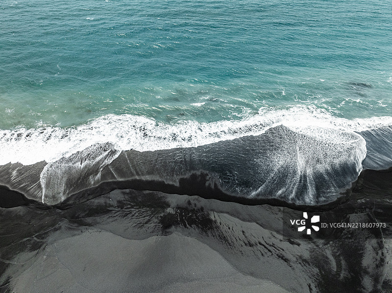 印度洋的海浪从空中视角拍摄，涌向巴厘岛克隆贡区的黑沙滩。图片素材