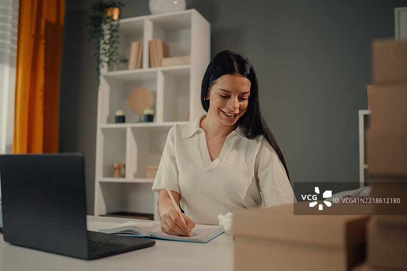 年轻女企业家在家办公室记录订单笔记图片素材