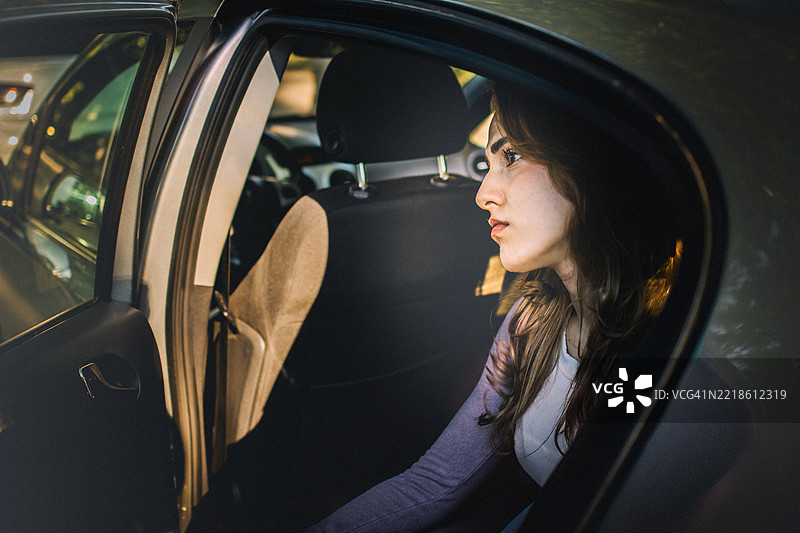 一位美丽年轻女性坐在车后座上，感到悲伤、无助和沮丧。图片素材