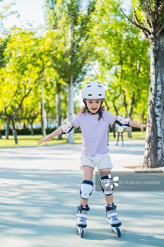 小女孩穿着保护装备在公园里享受滑旱冰的乐趣图片素材