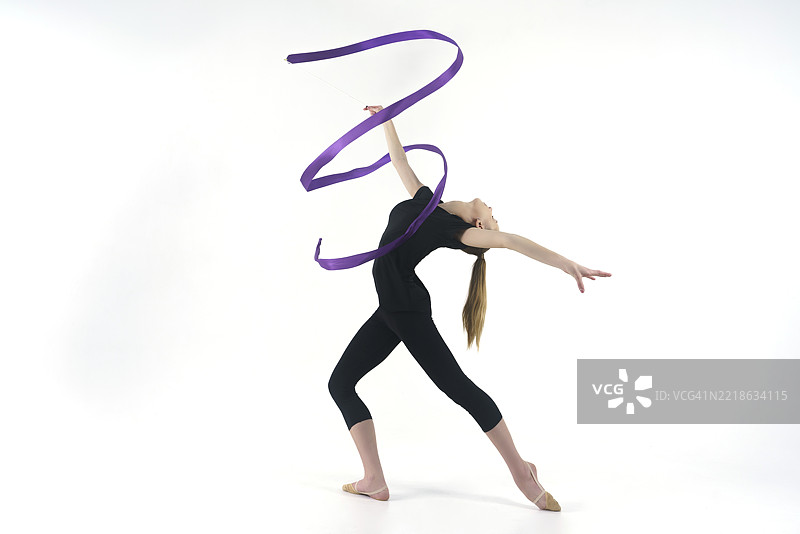年轻的体操运动员在摄影工作室展示用彩带进行的动作，做拉伸和旋转，位于俄罗斯西伯利亚的新西伯利亚。图片素材