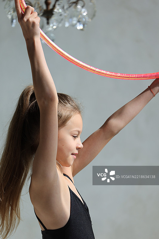 穿着黑色体操服的女孩在灰色背景下与圈子，艺术体操概念图片素材