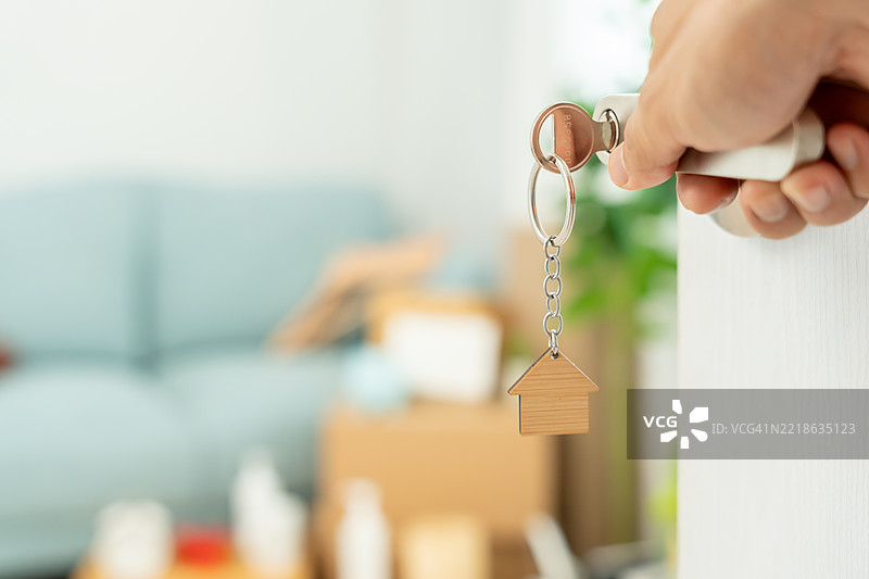 搬家，搬迁的情侣手持新公寓的钥匙钥匙扣，房间内有一辆车图片素材