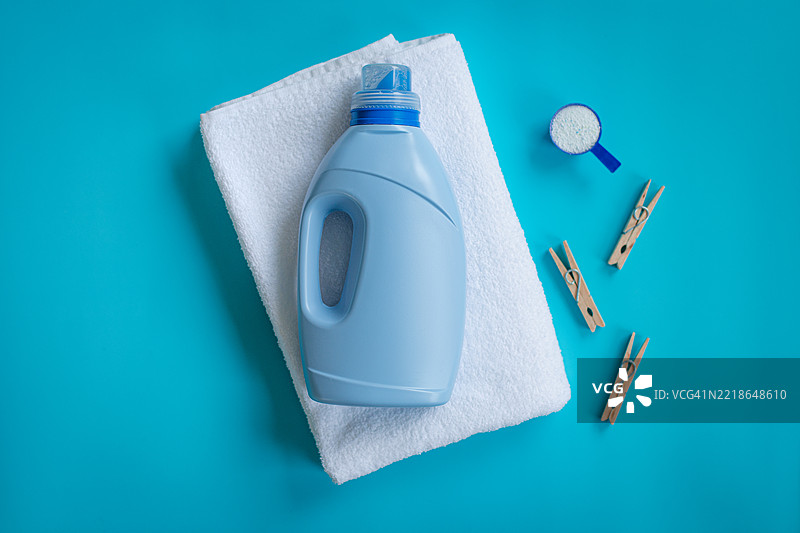 洗衣粉、白色毛巾和蓝色背景上的衣夹，象征着清洁和清新。图片素材