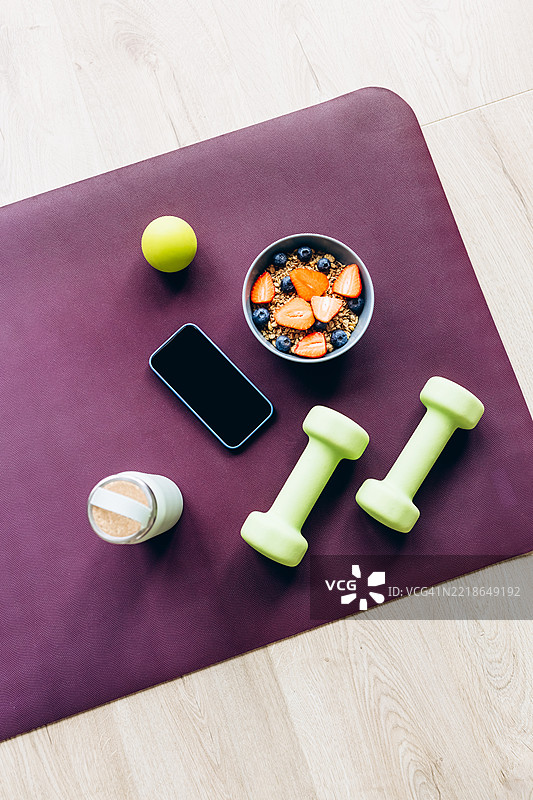 健康生活方式的平面布局，配有健身器材和早餐碗。完美展现了家庭中平衡的健身与营养。图片素材