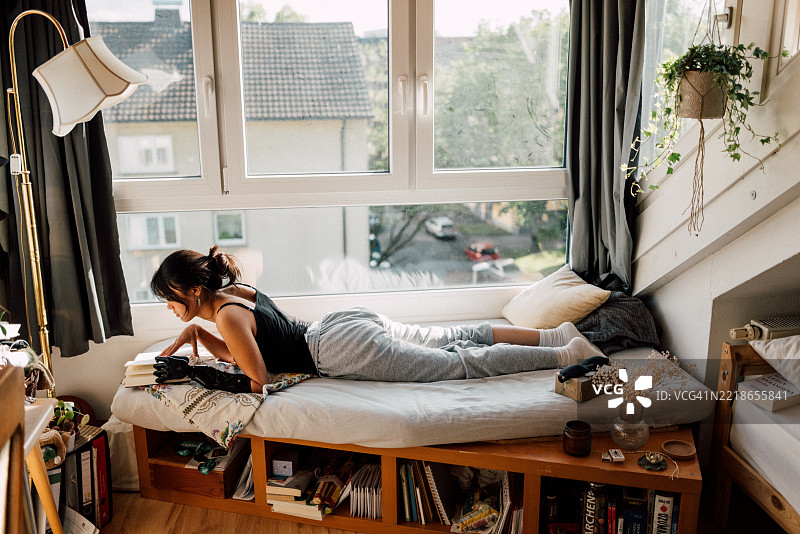 温馨的室内场景，展示一位女性在明亮的大窗户旁阅读图片素材