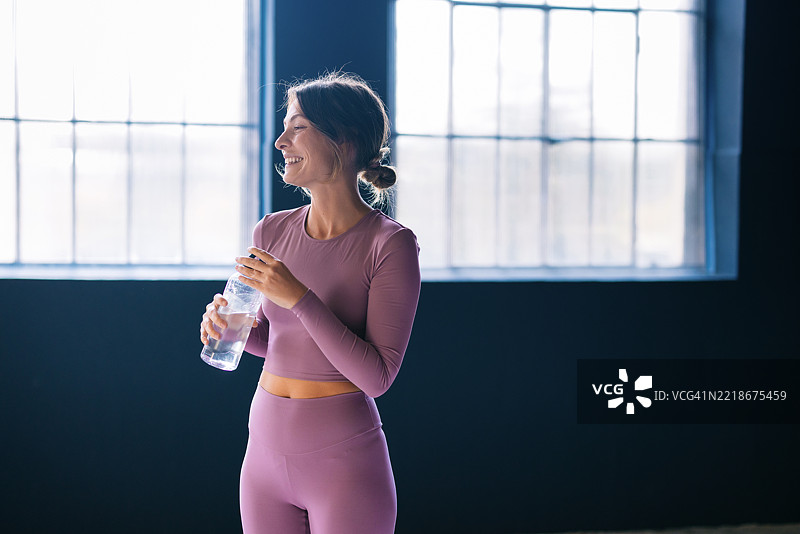 健身房里，女性在健身后喝水，感到神清气爽图片素材