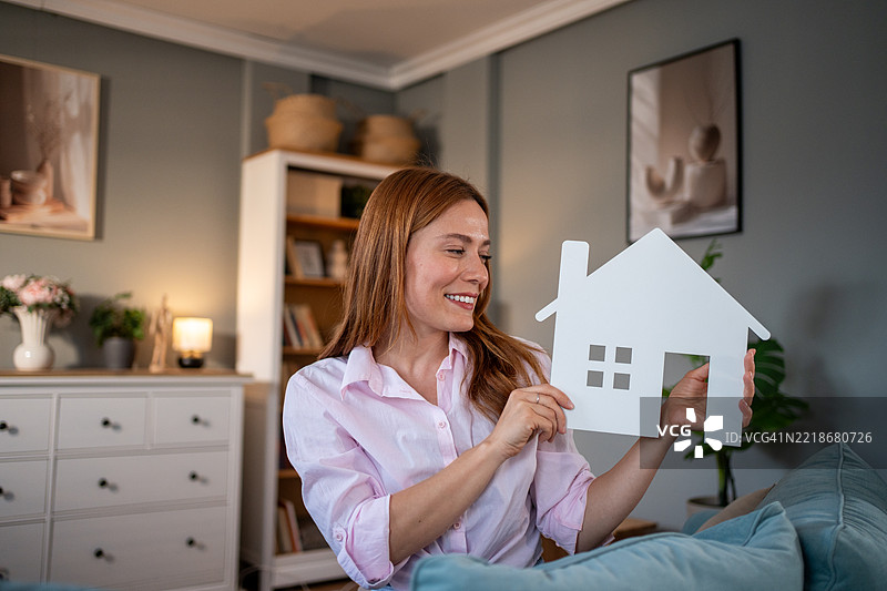 微笑的女人手里拿着一个小白色房子剪影图片素材