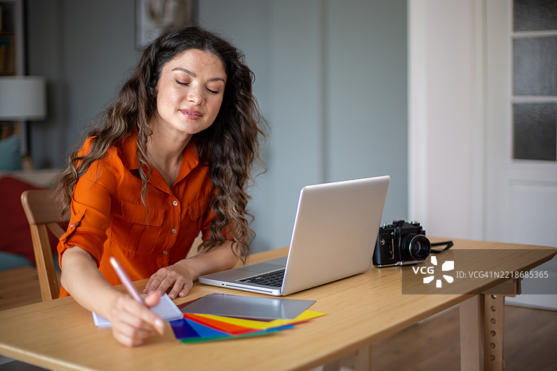 女性设计师在家中使用色卡和笔记本电脑工作图片素材