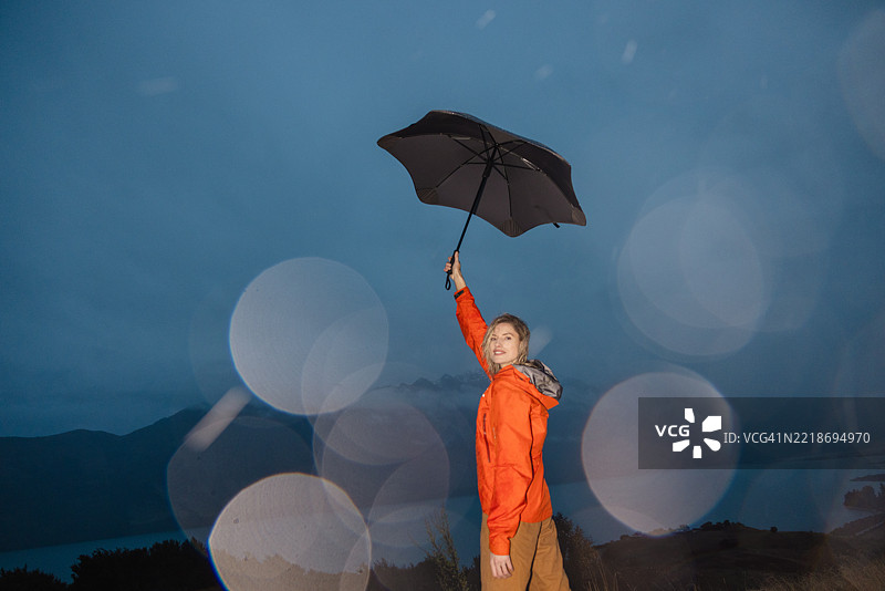 一位女性在阴郁的风景中撑着伞。图片素材