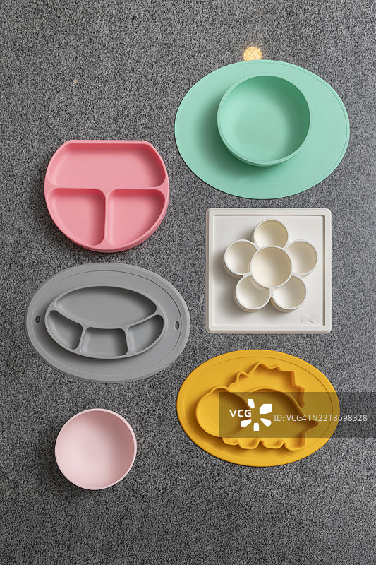 五颜六色的硅胶婴儿餐具放在深色台面上图片素材