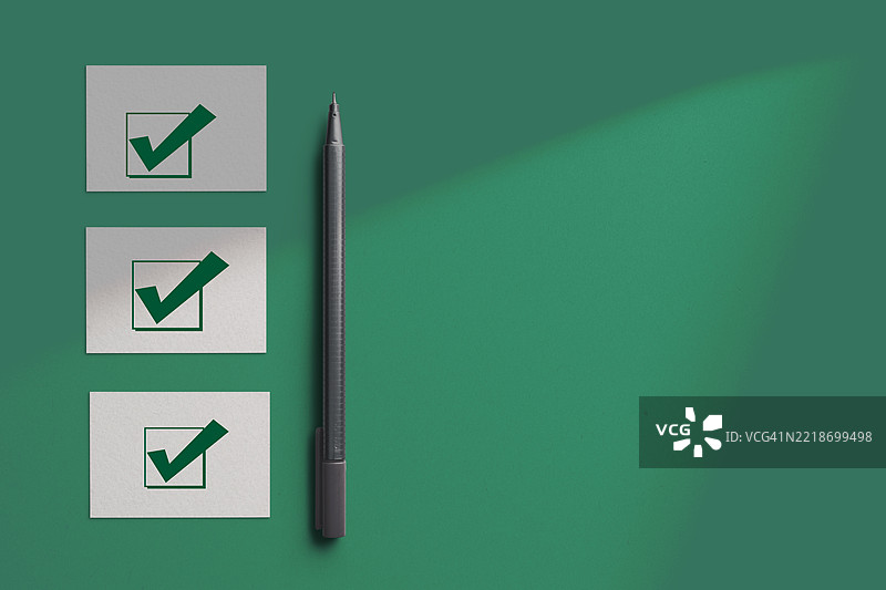 选择和挑选的概念。纸张上的绿色勾号和一支笔。图片素材