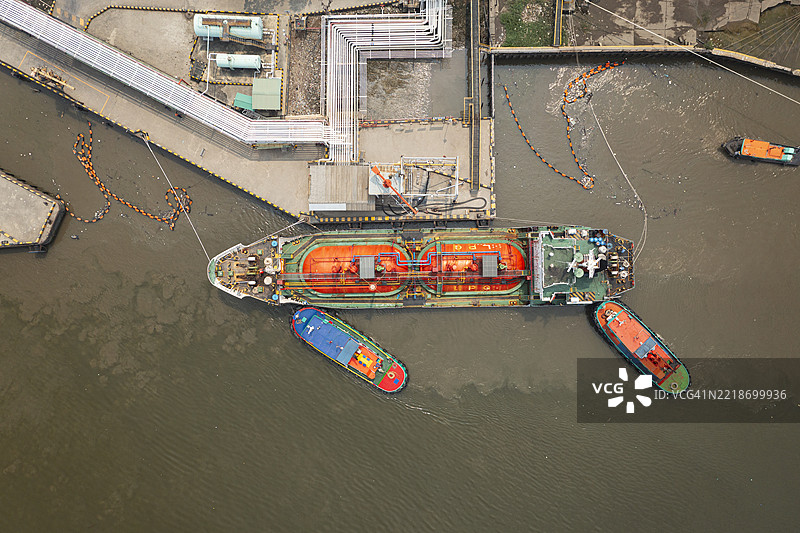航拍视角，拖船正在将油轮或液化石油气船拖向装载码头，以便运输来自炼油厂的油或液化石油气。图片素材