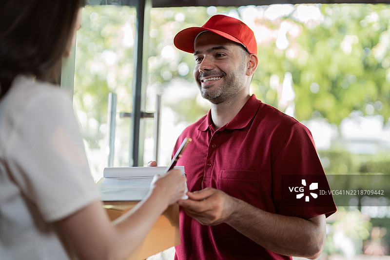 男性快递员在家中向顾客递送包裹。图片素材