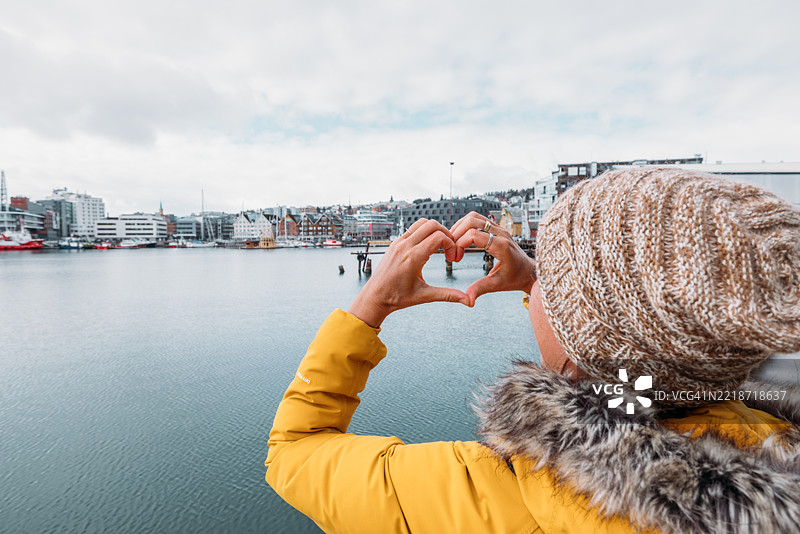 女人在风景如画的港口景观上用手做心形手势图片素材