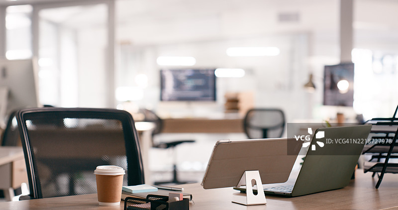 现代办公室工作空间，桌上有笔记本电脑和平板电脑，柔和的灯光照明。图片素材