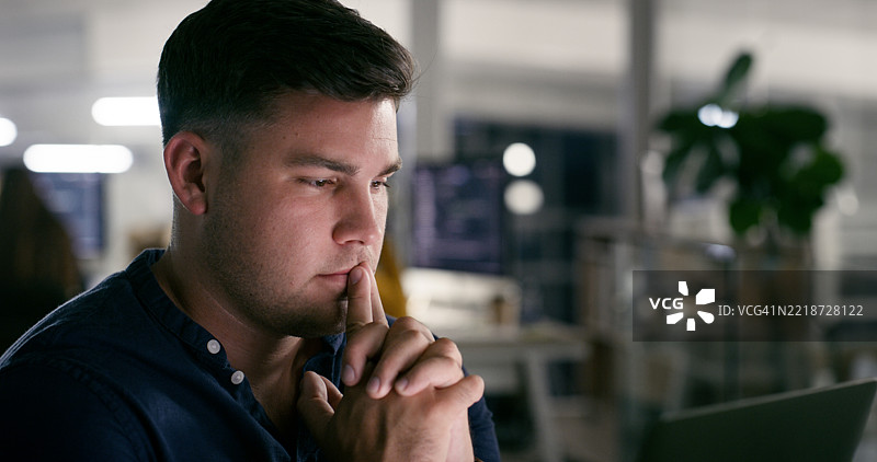 专注的专业人士在现代办公室环境中夜间使用笔记本电脑工作图片素材