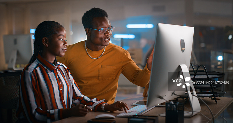 两位专业人士在现代办公室深夜合作图片素材