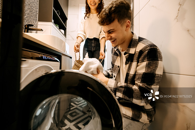 年轻情侣在洗衣时开心地微笑图片素材