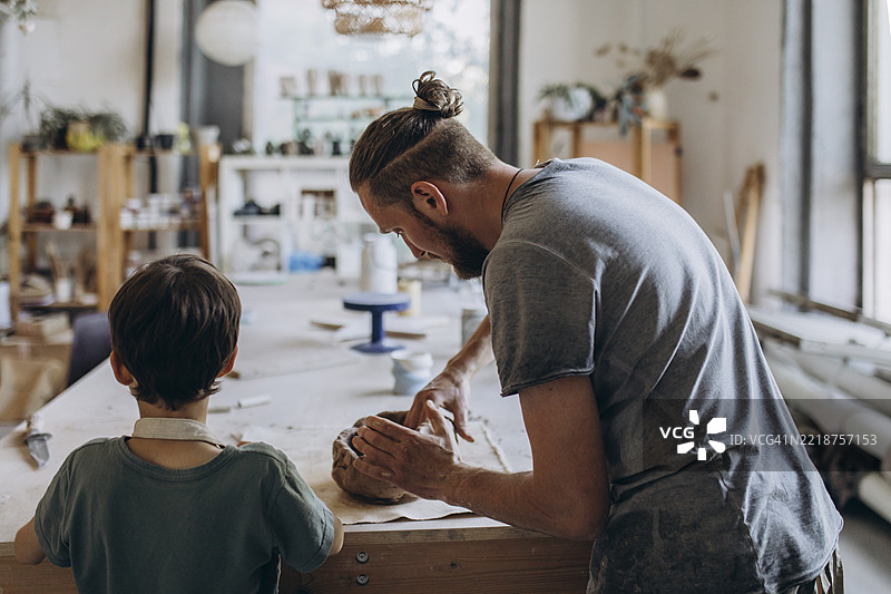 陶艺师在他的工作室教男孩图片素材