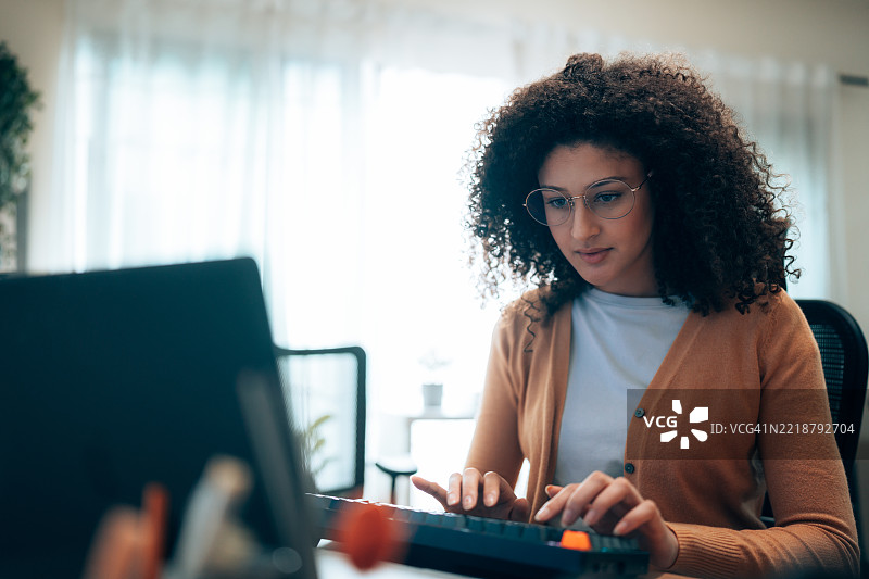 拉丁裔女性工程师在技术工作空间中使用笔记本电脑和外部显示器工作。图片素材