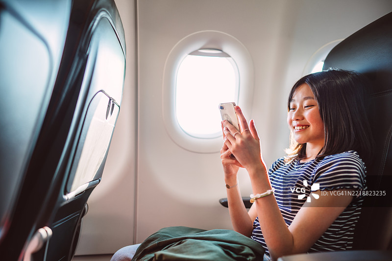 微笑的少女在飞行中使用智能手机图片素材